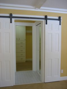 an open closet with sliding doors and drawers in the room that is painted yellow, white and gray