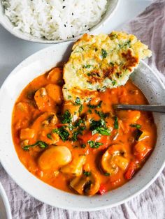 a white bowl filled with food next to rice