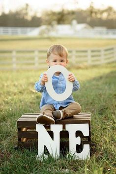 a little boy sitting on top of a wooden block with the letter nf in front of him