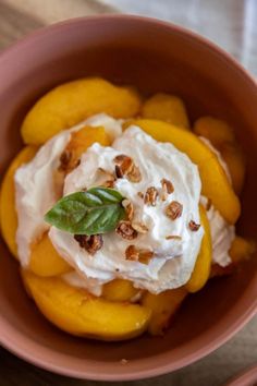 peaches and whipped cream in a bowl on top of a wooden table with utensils