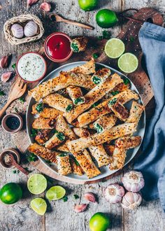 someone is cutting up some food on a plate with garlic and limes next to it