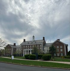 a large brick building sitting on the side of a road next to a lush green field