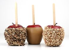 three apples with candles in them sitting side by side on a white surface and one has gold sprinkles