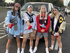 four young women standing in front of a car