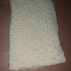 a white crocheted blanket laying on top of a wooden floor