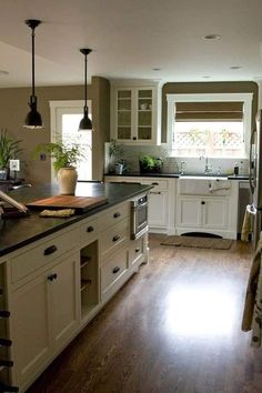 a large kitchen with white cabinets and wood flooring is seen in this image from the doorway