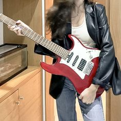 a woman holding a red electric guitar in her hand