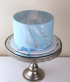 a blue cake with silver decorations on a platter and white tablecloth, ready to be served