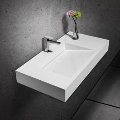 a white sink sitting on top of a counter next to a vase with flowers