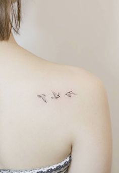 the back of a woman's shoulder with three birds tattoo on her left shoulder