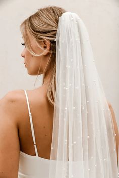 a woman wearing a white wedding veil with pearls on the back of her head and shoulder