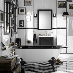 a black and white bathroom with an old fashioned bathtub in the center, framed pictures on the wall