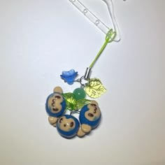 a blue and white beaded necklace with three bears on it, hanging from a hook