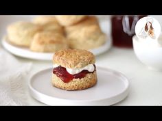 scones with jam and cream on them sitting on a white plate next to other pastries