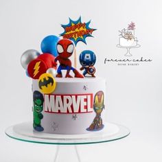 the birthday cake is decorated with superheros and balloons