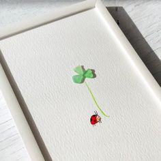 a four leaf clover with a ladybug on it's back in a white frame