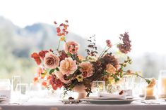 a vase filled with flowers sitting on top of a table next to plates and glasses