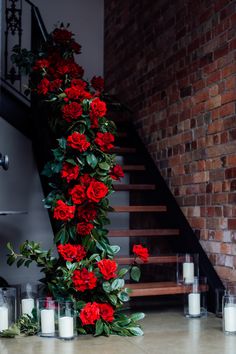 red roses and candles on the floor in front of a brick wall with stairs leading up to it