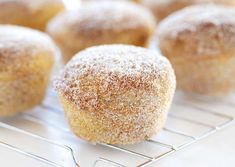 some sugared donuts are cooling on a wire rack and ready to be eaten