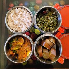 four metal bowls filled with different types of food on top of a glass countertop