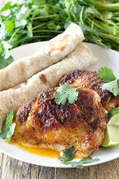 chicken with cilantro, lime and pita bread on a white plate next to green vegetables