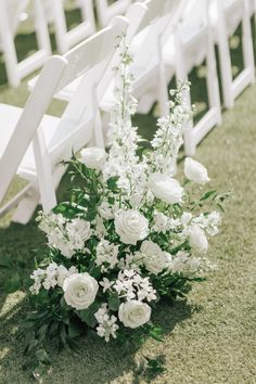 white flowers and greenery line the aisle of an outdoor ceremony