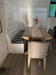 a table with two chairs and a bench in front of the window that has blinds on it