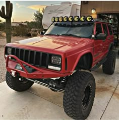 a red jeep is parked in front of a camper with its lights turned on