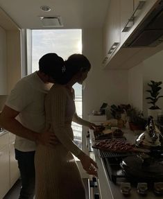 a man and woman standing in a kitchen next to an oven with food on the counter