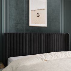 a bed with a black headboard in a bedroom next to a painting on the wall