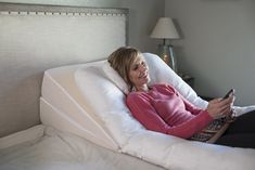 a woman laying in bed with a remote control