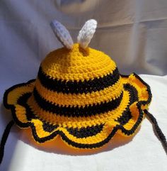 a crocheted hat with a bee on it sitting on a white cloth background