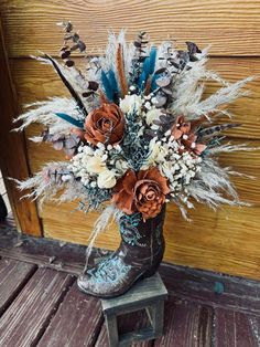 a cowboy boot with dried flowers and feathers on it sitting on a wooden step in front of a door