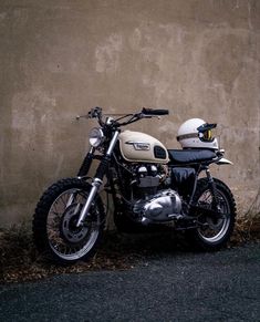 a motorcycle parked next to a wall with a helmet on it's back tire