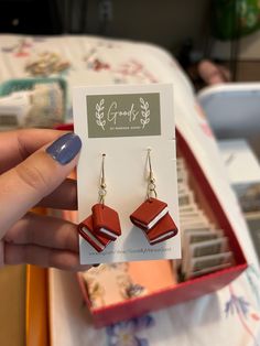 a pair of red and white earrings in a box on a table with other items