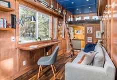 the interior of a tiny home with wood paneling and blue ceiling, two gray chairs