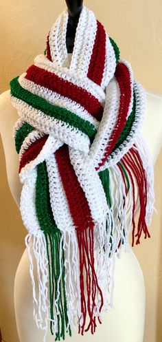 a white, red and green knitted scarf on a mannequin headpiece