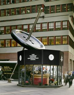 a large metal object sitting on top of a sidewalk next to a tall brick building