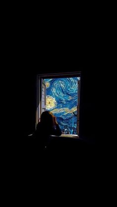 a person sitting in front of a window with the starry night painting on it