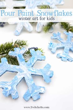 four snowflakes are shown with pine branches in the background and text overlay that says, pour paint snowflakes winter art for kids