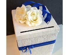 a white box with blue ribbon and flowers in it