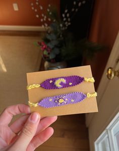 a person holding up a piece of paper with beads on it in front of a door