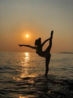 a woman standing on one leg in the water with her arms stretched out to balance