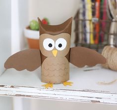 an owl made out of toilet paper sitting on top of a white shelf next to a spool of twine