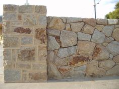 a stone wall next to a parking lot