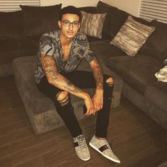 a man with tattoos sitting on a couch