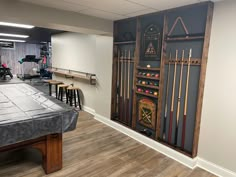 a room with a pool table and several game pieces on the wall, including cues