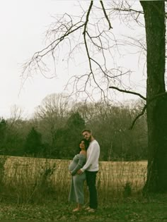 a man and woman standing next to each other near a tree