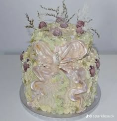 a decorated cake with flowers and pearls on it's side, sitting on a table