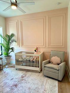 a baby's room with a crib, chair and potted palm tree